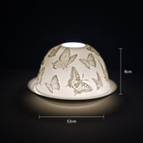 Cello porcelain tealight holder dome featuring scattered butterflies surrounding the dome. Dimensions: 8cm height, 12cm width, displayed against a dark background.