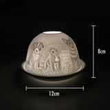 Cello porcelain tealight holder dome featuring puppies gathered together and surrounded by long grass. Dimensions: 8cm height, 12cm width, displayed against a dark background.