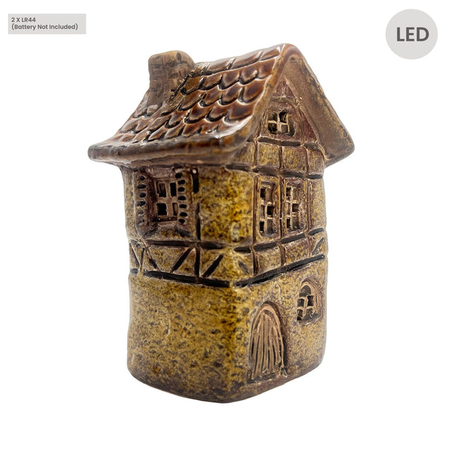 Front angle view of Cello Tales from the Village Silk Weaver’s Cottage LED ceramic house in yellow, showing detailed brickwork and illuminated windows.