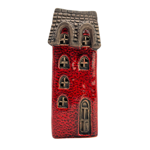 Front view of the Scribe’s Retreat village pottery house with softly glowing LED light shining through arched windows and rustic red brickwork.