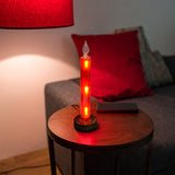 Red Gleneagles Moving Stars LED USB Glass Candle glowing warmly on a side table in a cosy living room, creating a festive, romantic ambience with its swirling star light effect.