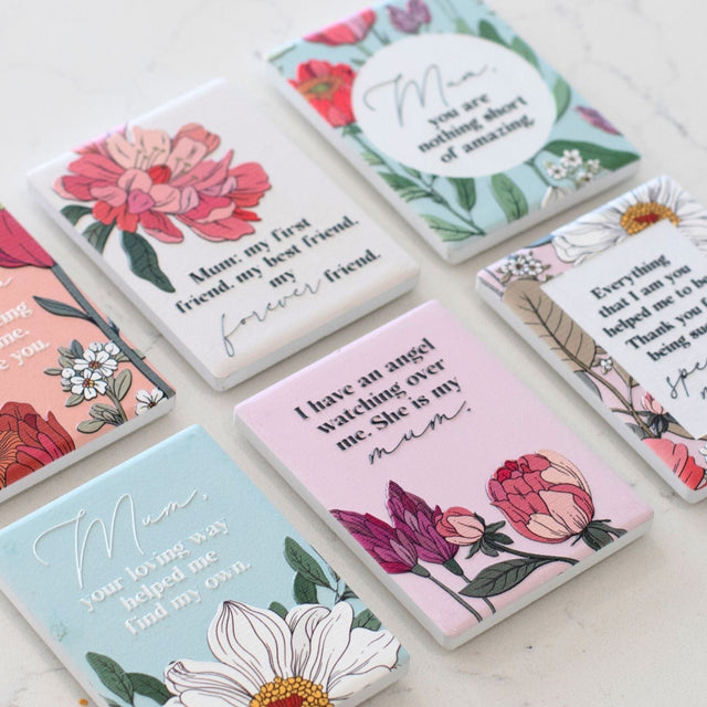 Set of decorative ceramic magnets with floral designs and heartfelt messages on a light surface as unique gift for mother's day