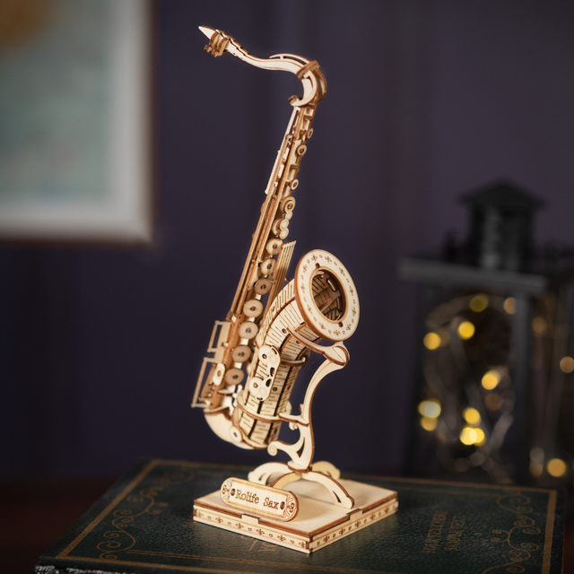 Wooden ROBOTIME Rolife Kits Saxophone TG309 on a book with a blurred background
