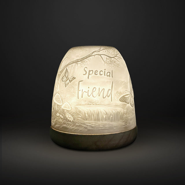 Cello Tall Tealight Dome Special Friend glowing porcelain candle holder on dark background.