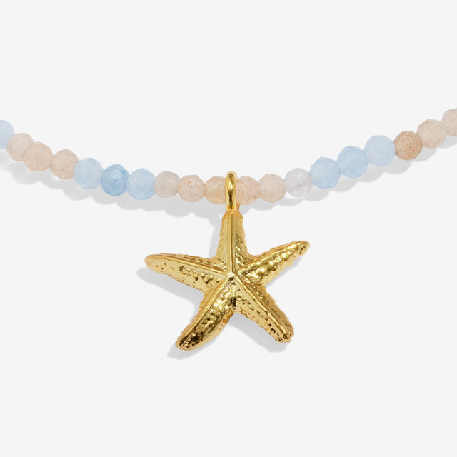 Close-up detail of gold anklet starfish charm and beaded chain