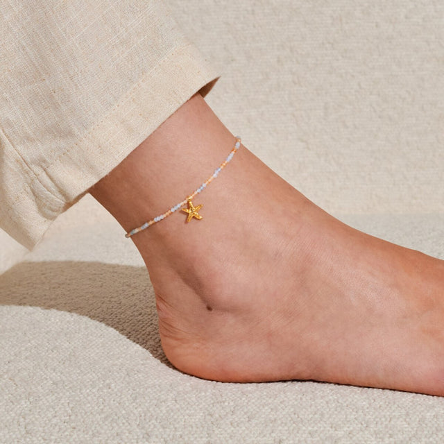 Gold anklet with starfish charm and pastel beads worn on ankle