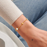 Gold clover bracelet worn on wrist with mother of pearl clover charms