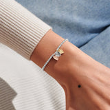 Mixed metal heart charm birthday bracelet worn on wrist