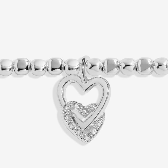 Close up of interlinked heart charms on silver sister bracelet