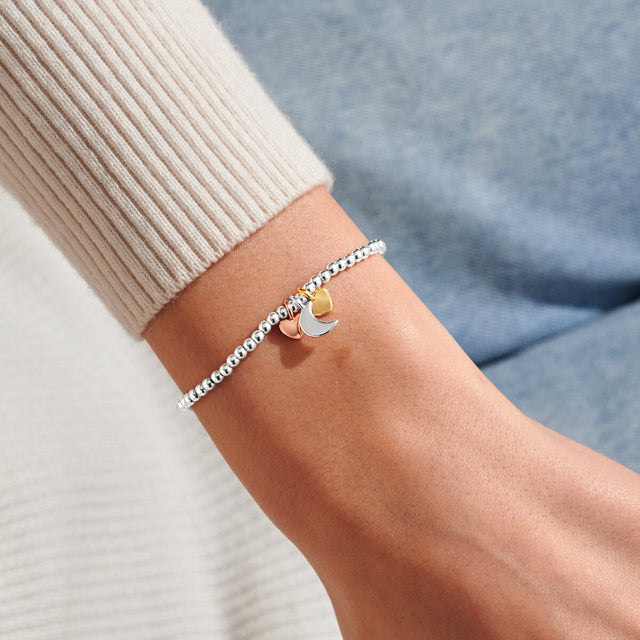 Mixed metal moon and heart charm bracelet worn on wrist