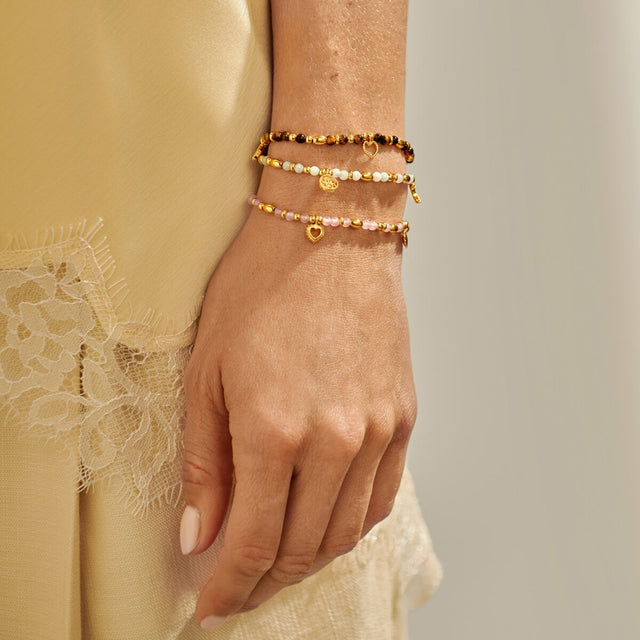 Joma Jewellery layered gold bracelets worn together lifestyle image