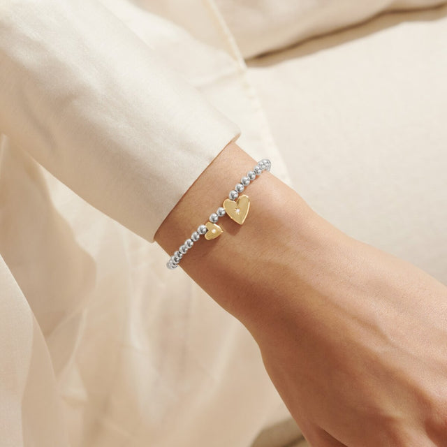 Silver and gold heart charm bracelet for sister worn on wrist