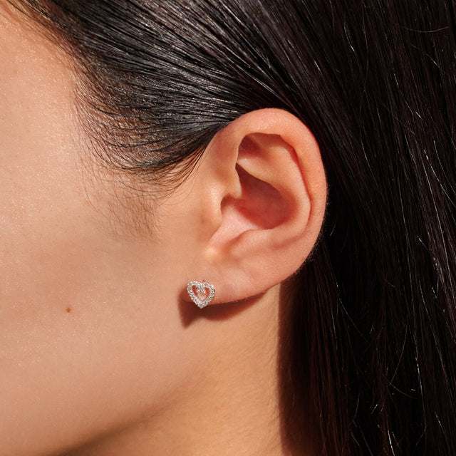 Silver heart earrings worn on ear
