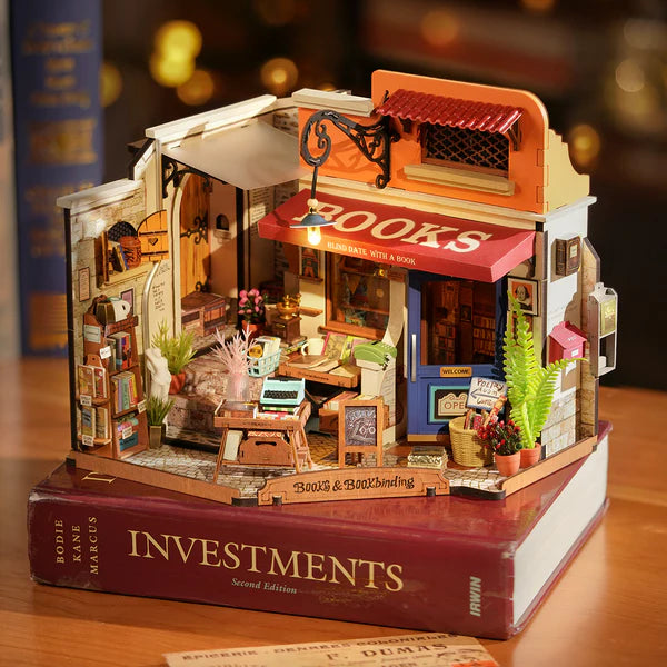 Robotime Rolife Corner Bookstore miniature model showing alleyway bookshop with books, plants and signage