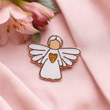 Angel of Friendship guardian angel pin displayed on pink fabric with floral details, symbolising warmth and affection.
