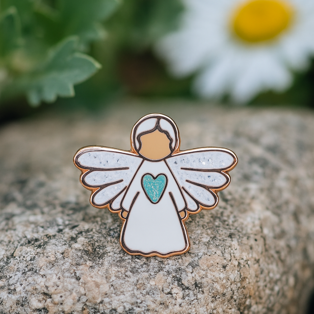 Angel of Hope guardian angel pin photographed outdoors among daisies, symbolising light, renewal, and encouragement.