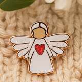 Angel of Strength guardian angel pin resting on soft knitted fabric, symbolising comfort, hope, and encouragement.