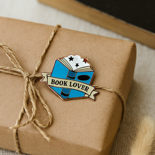 Splosh Book Lover enamel pin displayed on brown gift wrap with ribbon