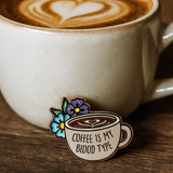 Splosh Coffee Lover enamel pin styled beside a latte in a cosy café setting