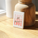 Love-themed ceramic magnet displayed on a jar surface