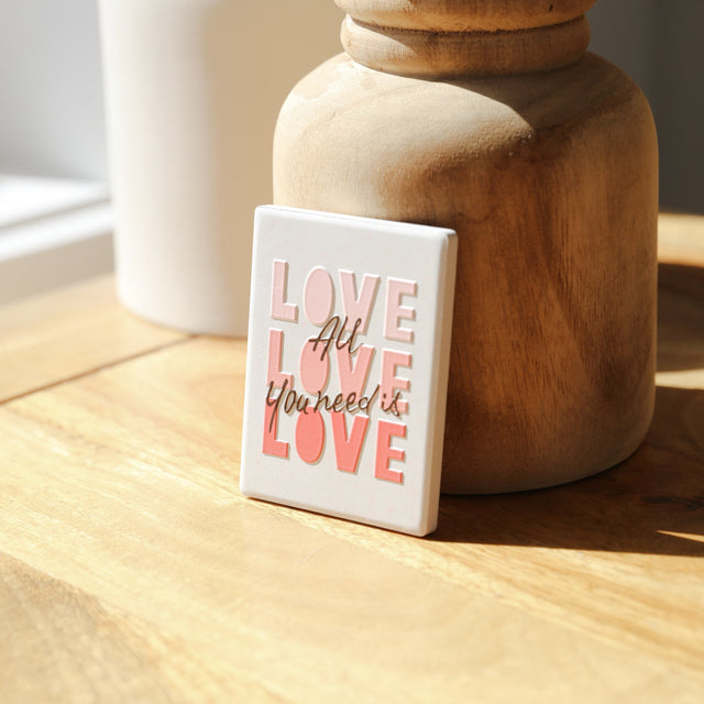 Love-themed ceramic magnet displayed on a jar surface